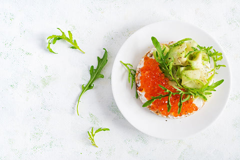 Rice Cracker with Cream Cheese, Avocado and Salmon Roe on a white plate.